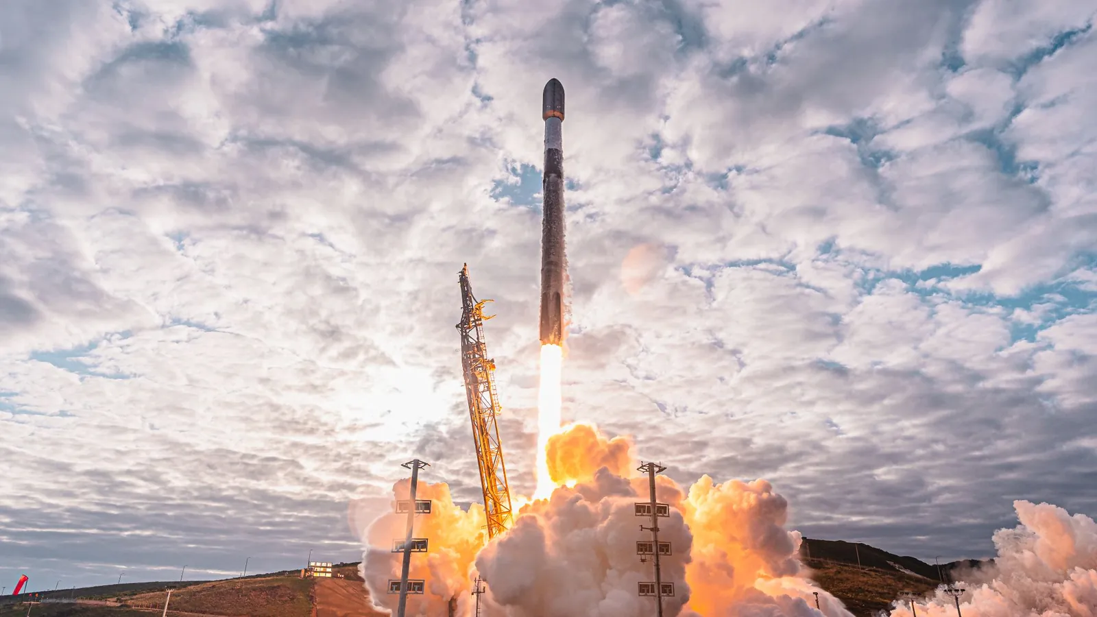 a black-and-white spacex falcon 9 rocket launches into a cloudy sky.