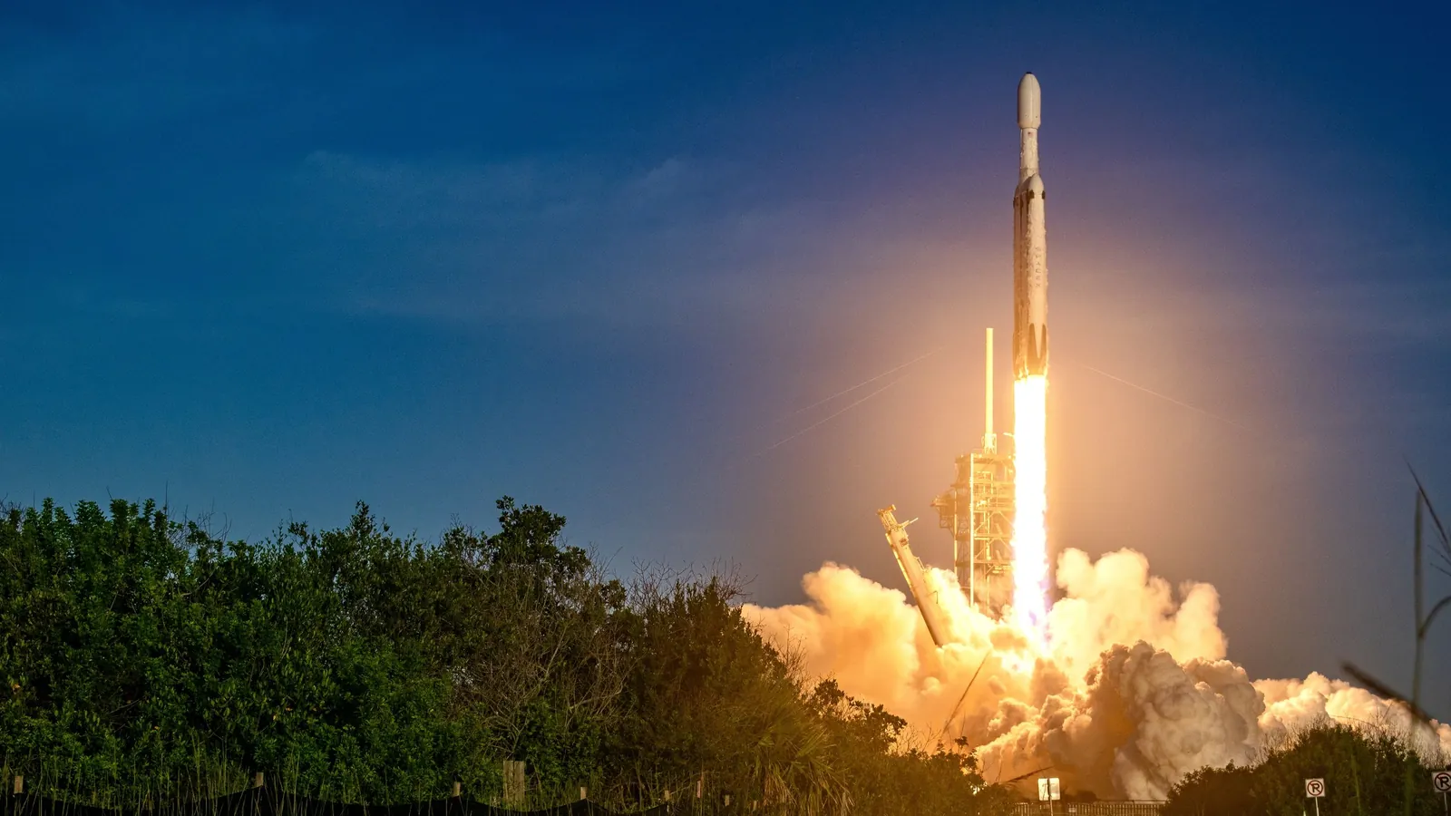 A rocket launches, leaving behind a fiery trail.