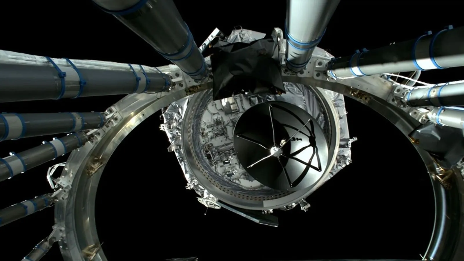 a hexagonal spacecraft floats away from a large metal ring on a black background