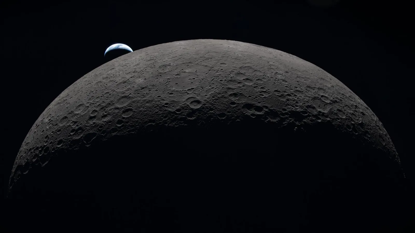 A view of the moon in the foreground with a small Earth in the background.